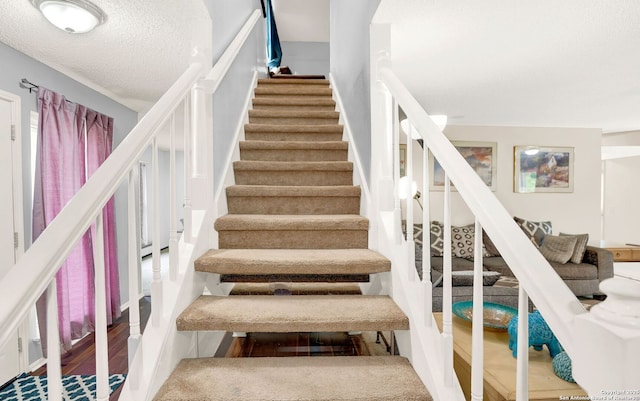 stairs with a textured ceiling and wood finished floors