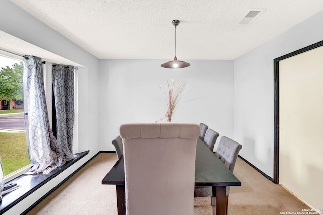 dining room with visible vents, a textured ceiling, baseboards, and light carpet