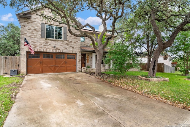 traditional-style home with a garage, fence, concrete driveway, and brick siding
