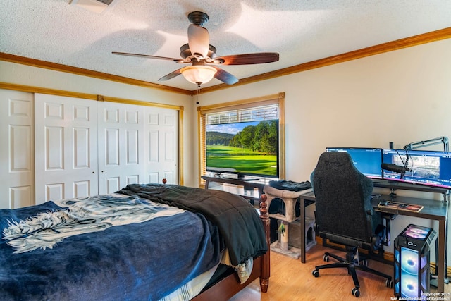 bedroom with ceiling fan, a textured ceiling, wood finished floors, a closet, and ornamental molding