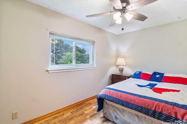 bedroom with a ceiling fan, baseboards, wood finished floors, and a textured ceiling