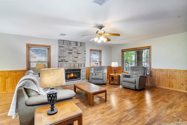 living area featuring wood walls, visible vents, wainscoting, and light wood-style flooring