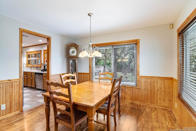 6763 Shadow Run, San Antonio, TX 78250 - dining area with a chandelier, wood walls, wainscoting, and light wood-type flooring