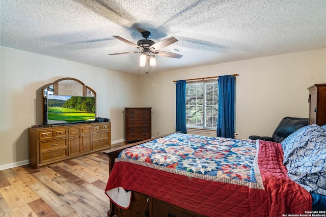 bedroom with a ceiling fan, a textured ceiling, baseboards, and light wood-type flooring