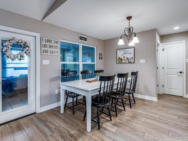 dining area with baseboards, light wood-style flooring, and a notable chandelier