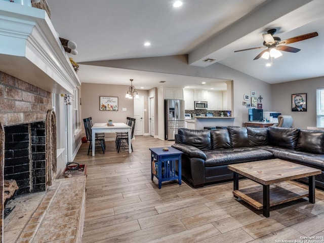 living area with visible vents, lofted ceiling with beams, light wood-style floors, and a fireplace