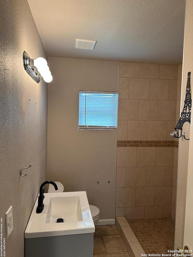 full bath with visible vents, tile patterned flooring, vanity, toilet, and a tile shower