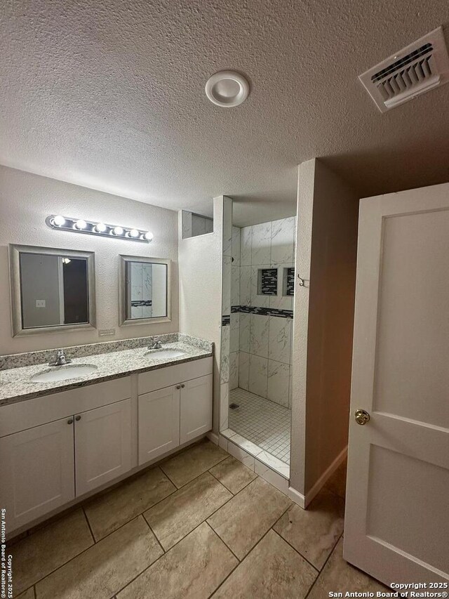 bathroom featuring visible vents, a sink, a textured ceiling, and a shower stall