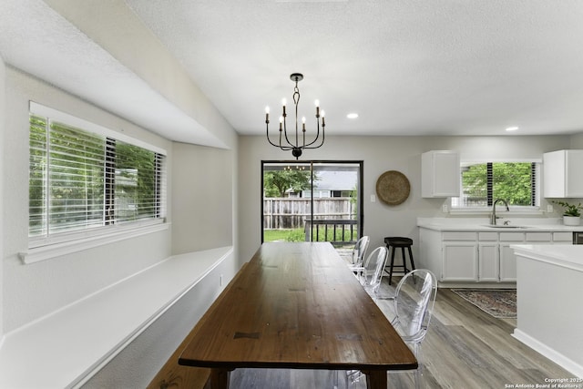 dining area featuring a textured ceiling, recessed lighting, wood finished floors, and a notable chandelier