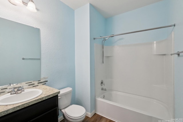 bathroom featuring vanity, wood finished floors, toilet, baseboards, and shower / bathing tub combination