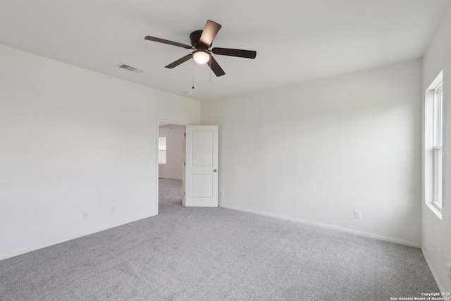 carpeted spare room with a healthy amount of sunlight, ceiling fan, and visible vents
