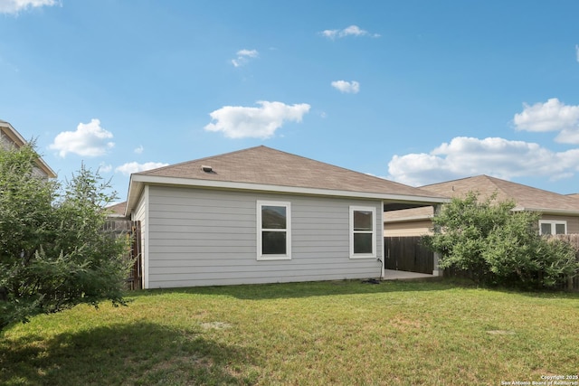 rear view of house with a lawn and fence