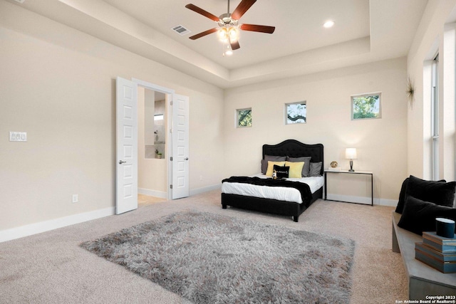 carpeted bedroom with recessed lighting, a tray ceiling, visible vents, and baseboards