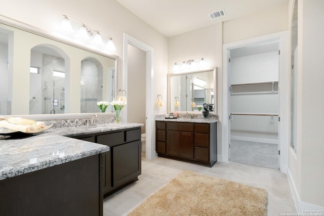 full bath featuring visible vents, a sink, a walk in closet, and a shower stall