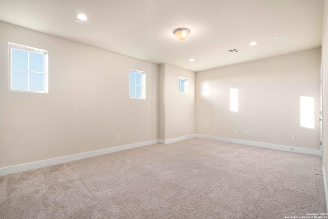 spare room with light colored carpet, recessed lighting, baseboards, and visible vents