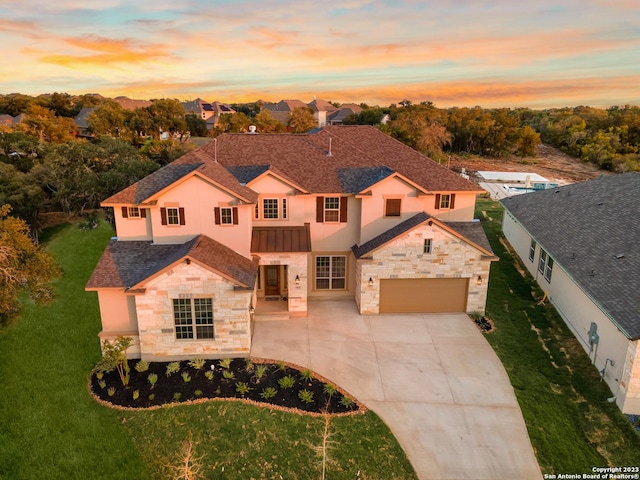 traditional-style house featuring stucco siding, concrete driveway, a front lawn, and stone siding