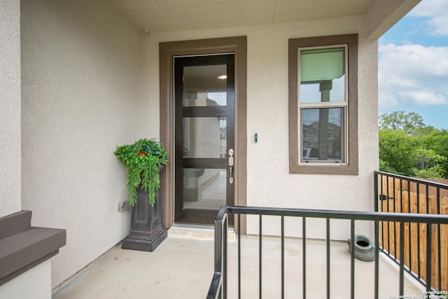 property entrance with a balcony and stucco siding