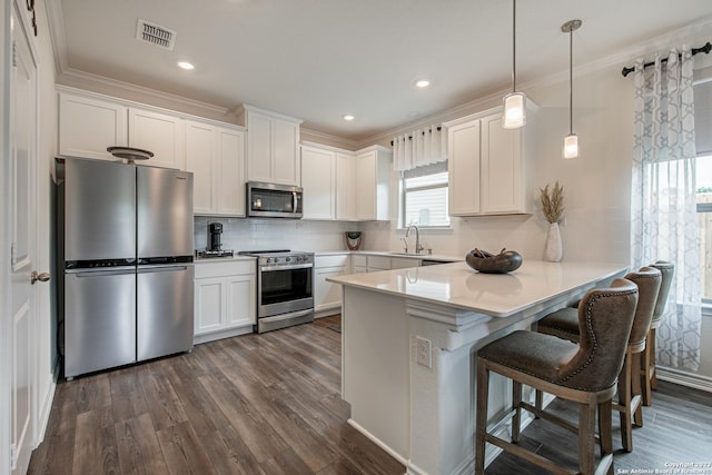 kitchen with a peninsula, stainless steel appliances, dark wood-style flooring, and visible vents