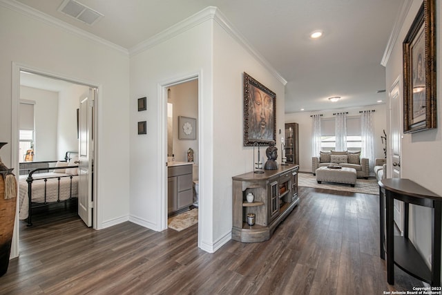 hall with dark wood-type flooring, ornamental molding, and a wealth of natural light
