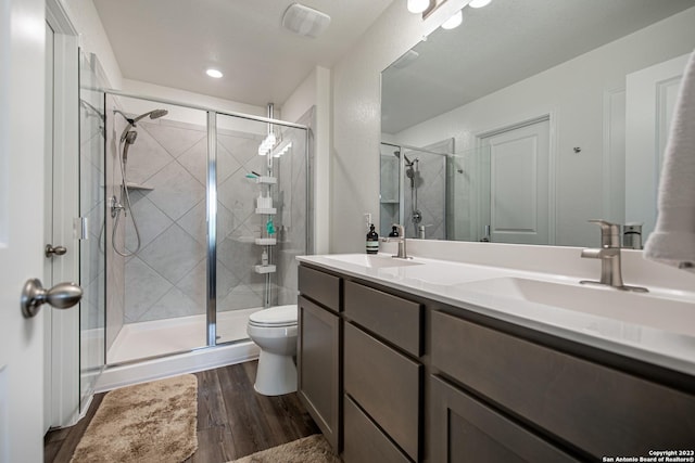 full bathroom featuring a sink, wood finished floors, toilet, and a shower stall