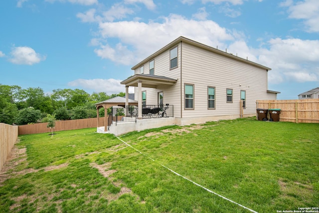 rear view of house featuring a fenced backyard, a gazebo, and a lawn