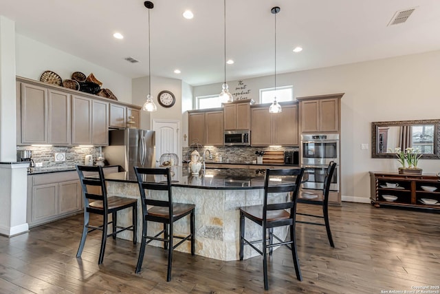 kitchen featuring stainless steel appliances, visible vents, a kitchen breakfast bar, and tasteful backsplash