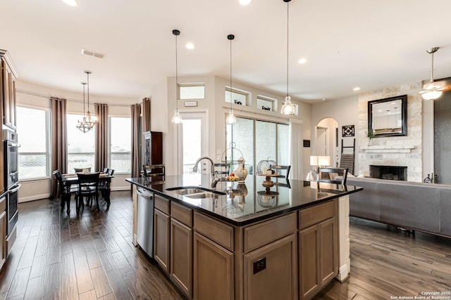 kitchen with dark wood-style flooring, a sink, arched walkways, a stone fireplace, and visible vents