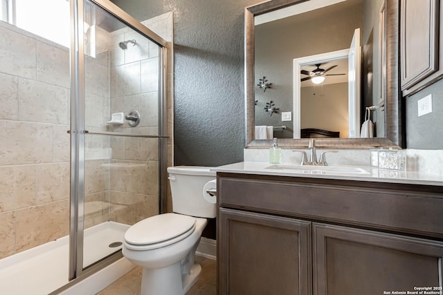 bathroom with vanity, a textured wall, toilet, ceiling fan, and a stall shower