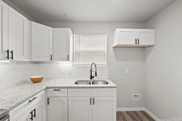 kitchen with dark wood-type flooring, a sink, decorative backsplash, and baseboards