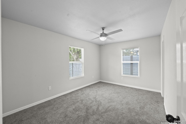 carpeted spare room featuring ceiling fan, plenty of natural light, and baseboards