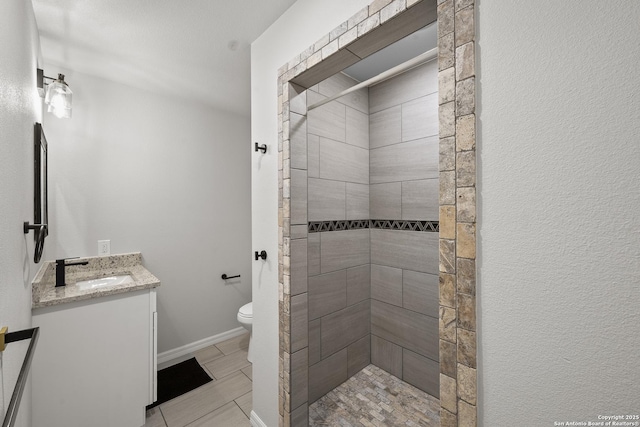 full bath featuring tile patterned flooring, a stall shower, vanity, baseboards, and toilet