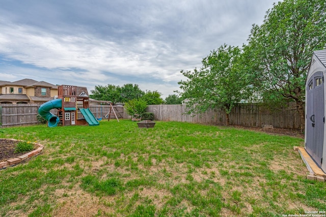view of yard with a fire pit, a fenced backyard, and a playground