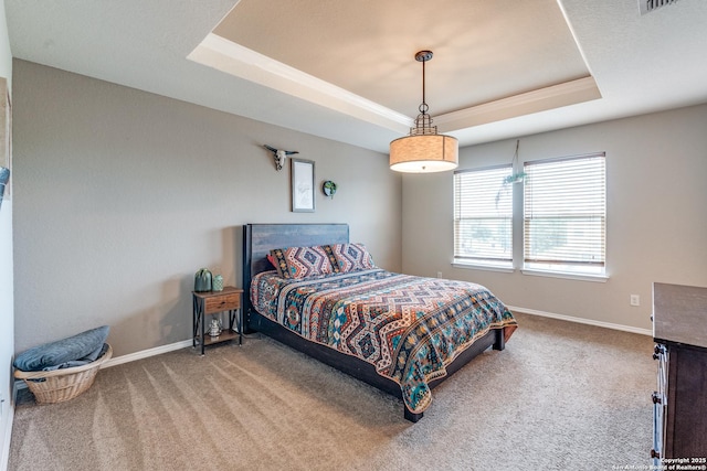 carpeted bedroom featuring a tray ceiling, visible vents, and baseboards
