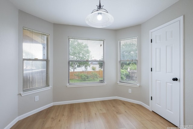 unfurnished dining area featuring light wood-type flooring, baseboards, and a chandelier