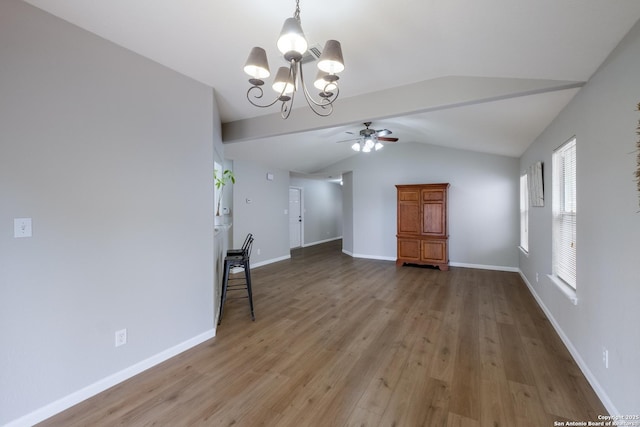interior space featuring baseboards, ceiling fan with notable chandelier, light wood-style flooring, and lofted ceiling