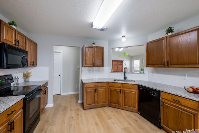 kitchen with visible vents, tasteful backsplash, a sink, black appliances, and light wood-style floors