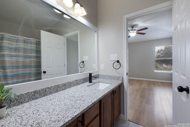 bathroom featuring vanity, wood finished floors, baseboards, a shower with shower curtain, and a ceiling fan