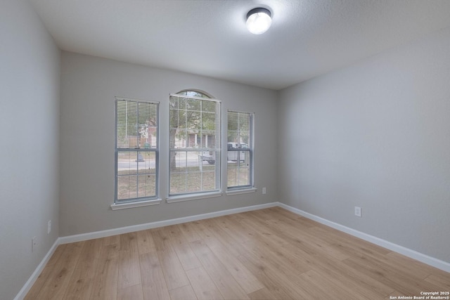 spare room featuring light wood-style floors and baseboards