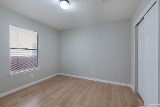 unfurnished bedroom featuring a closet, baseboards, and light wood-type flooring