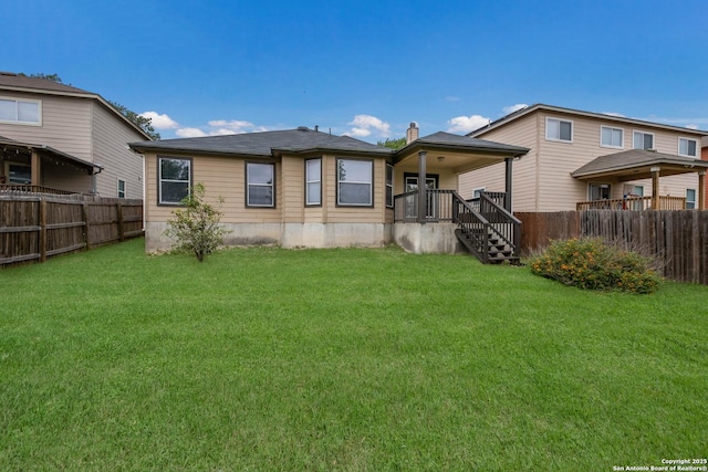 back of house with a lawn and a fenced backyard