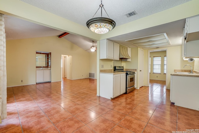 kitchen with stainless steel range, a sink, light countertops, light tile patterned floors, and visible vents