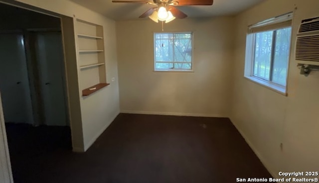 spare room featuring a ceiling fan, baseboards, and built in shelves