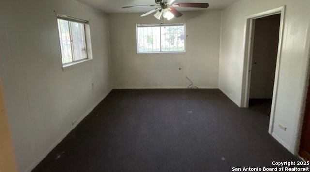 interior space with dark carpet and ceiling fan
