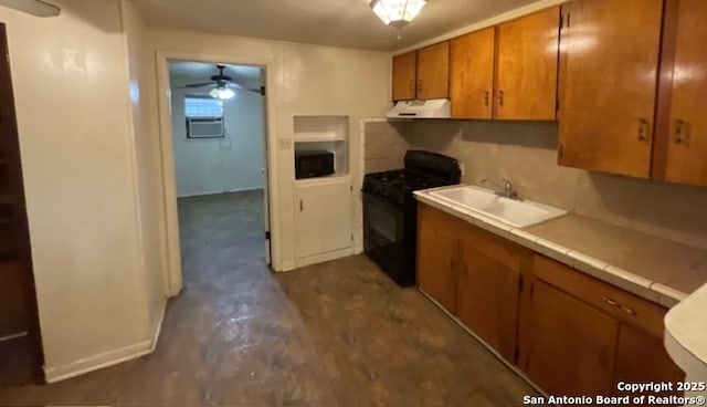 kitchen featuring a sink, gas stove, brown cabinets, a ceiling fan, and exhaust hood