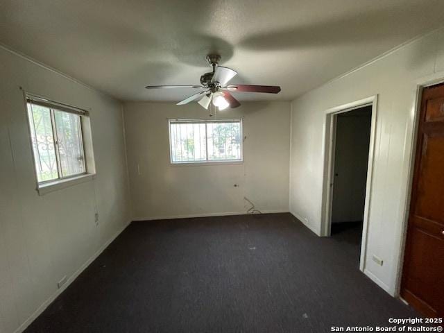 unfurnished bedroom with ceiling fan and dark carpet