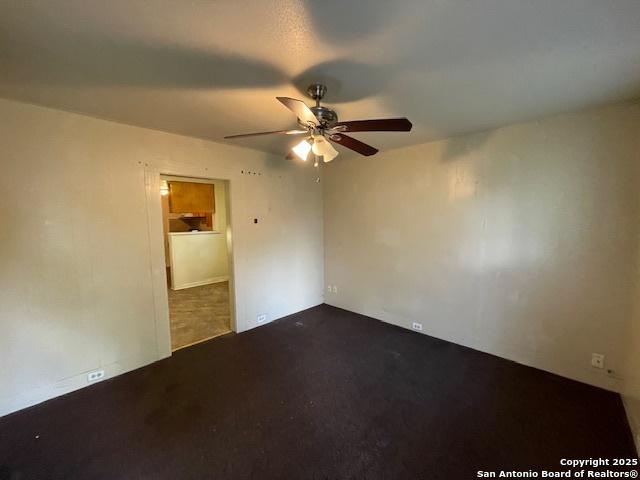 spare room with dark carpet and a ceiling fan
