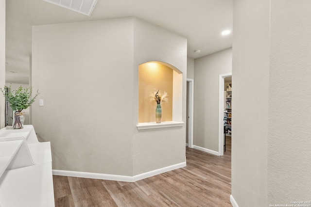 corridor with baseboards, wood finished floors, and visible vents
