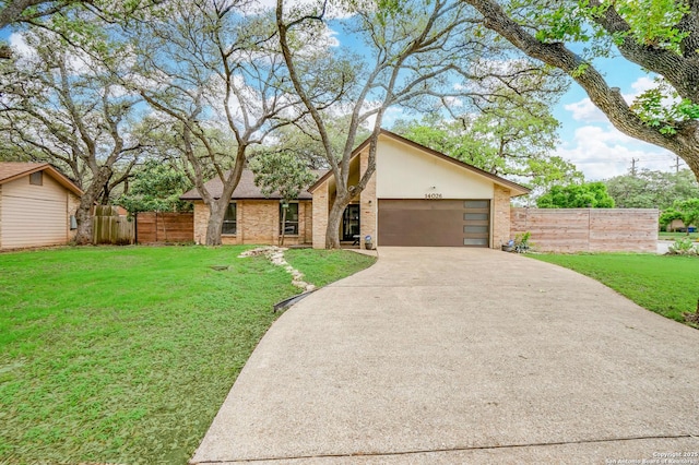 mid-century modern home with fence, a front lawn, brick siding, a garage, and concrete driveway