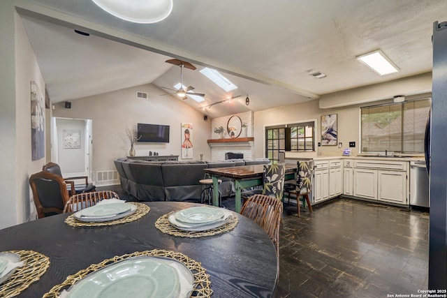 dining space featuring visible vents, lofted ceiling with skylight, a fireplace, and ceiling fan