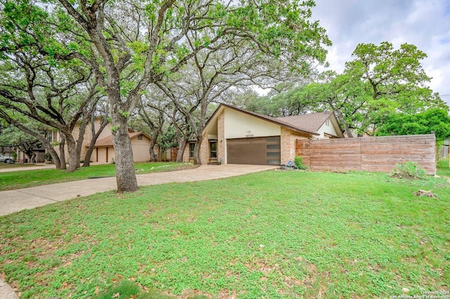 mid-century inspired home with fence, a front yard, stucco siding, brick siding, and driveway